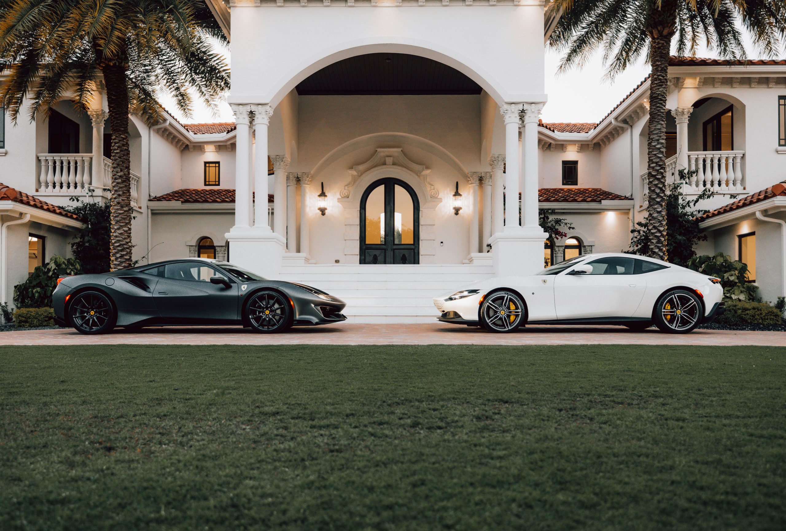Elegant mansion exterior with sleek sports cars in the driveway, illustrating an extravagant luxury lifestyle