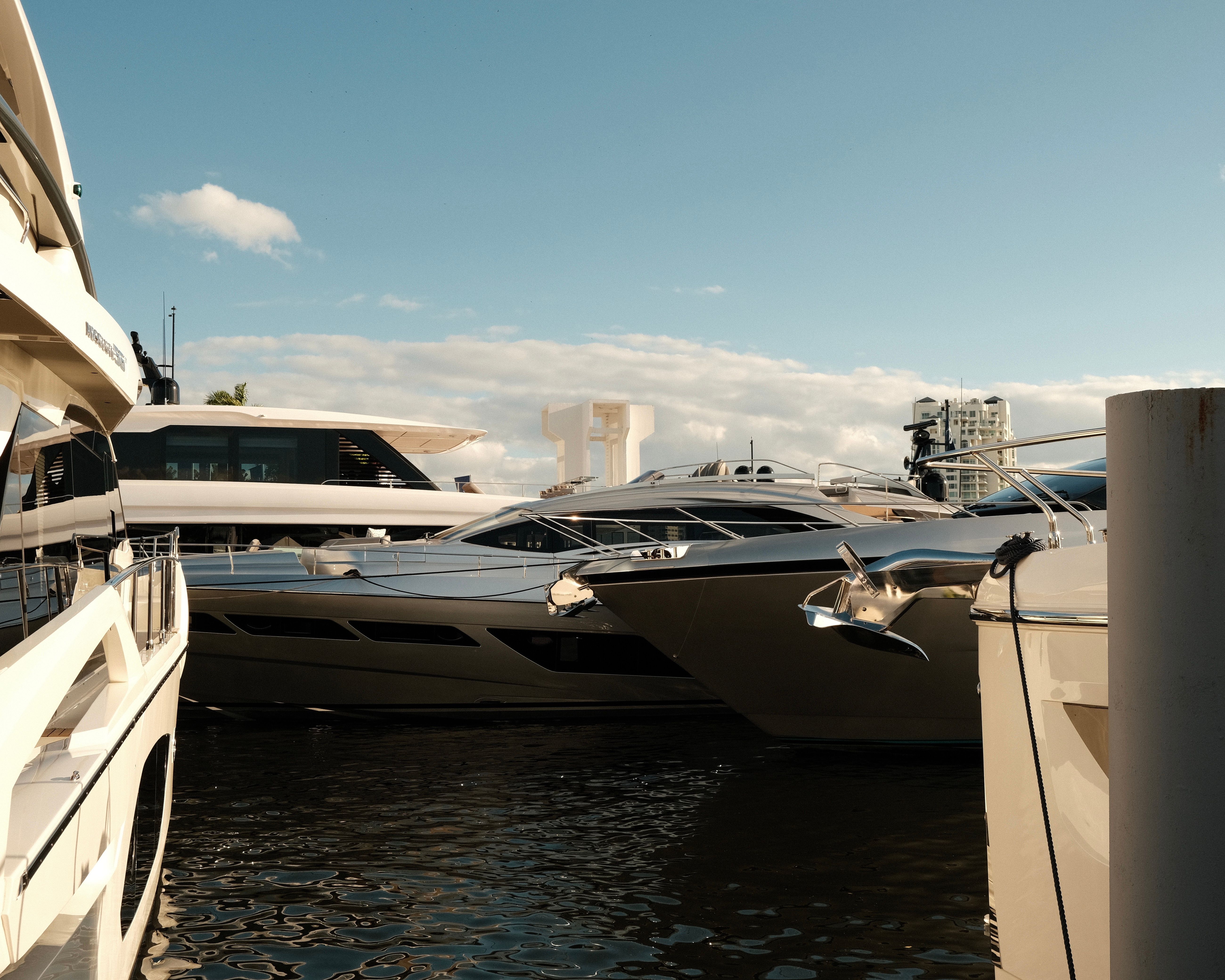 Several luxury yachts anchored at a sunny marina representing excessive luxury lifestyle spending