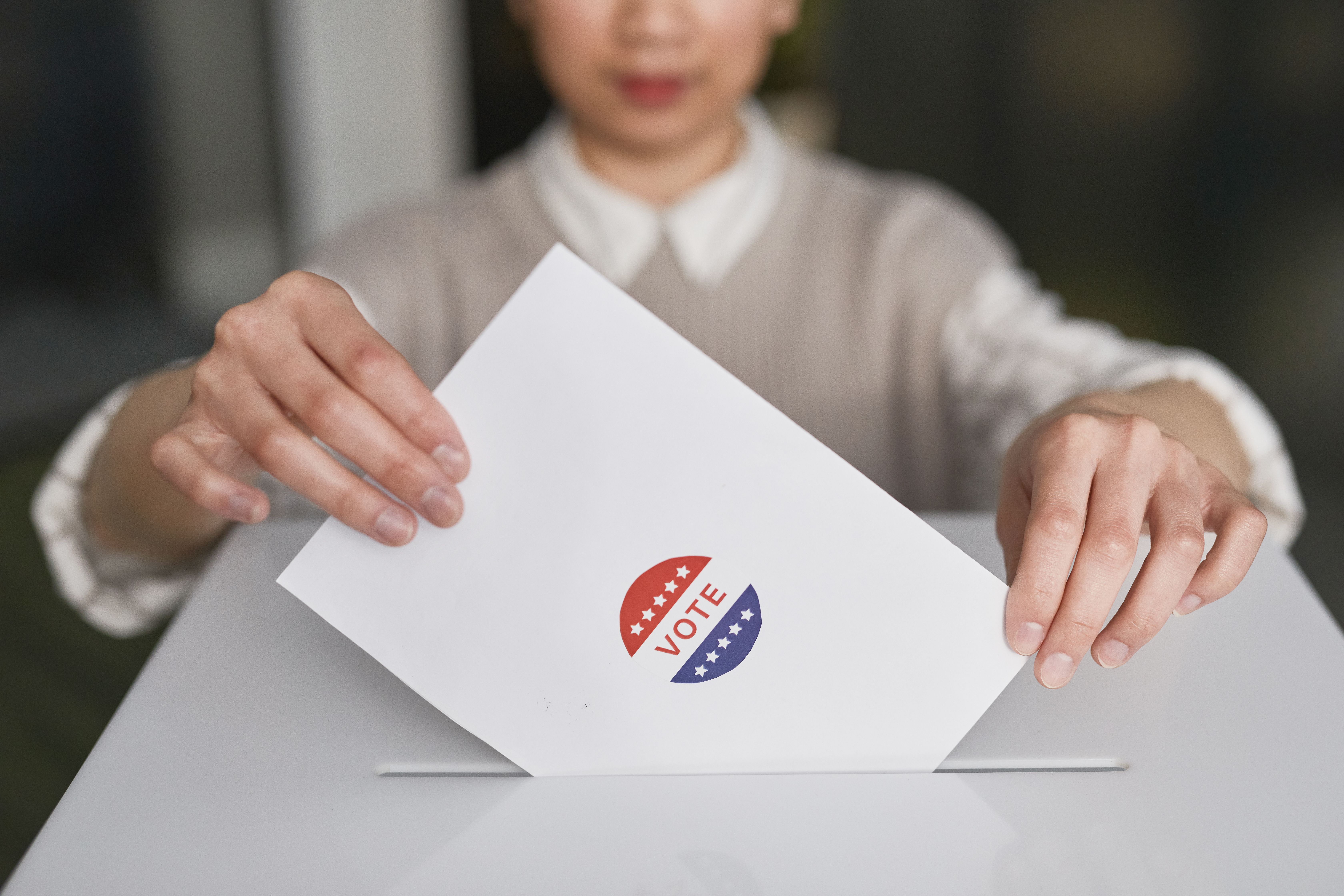 A person casting a ballot into a ballot box, representing elections and coalition shifts