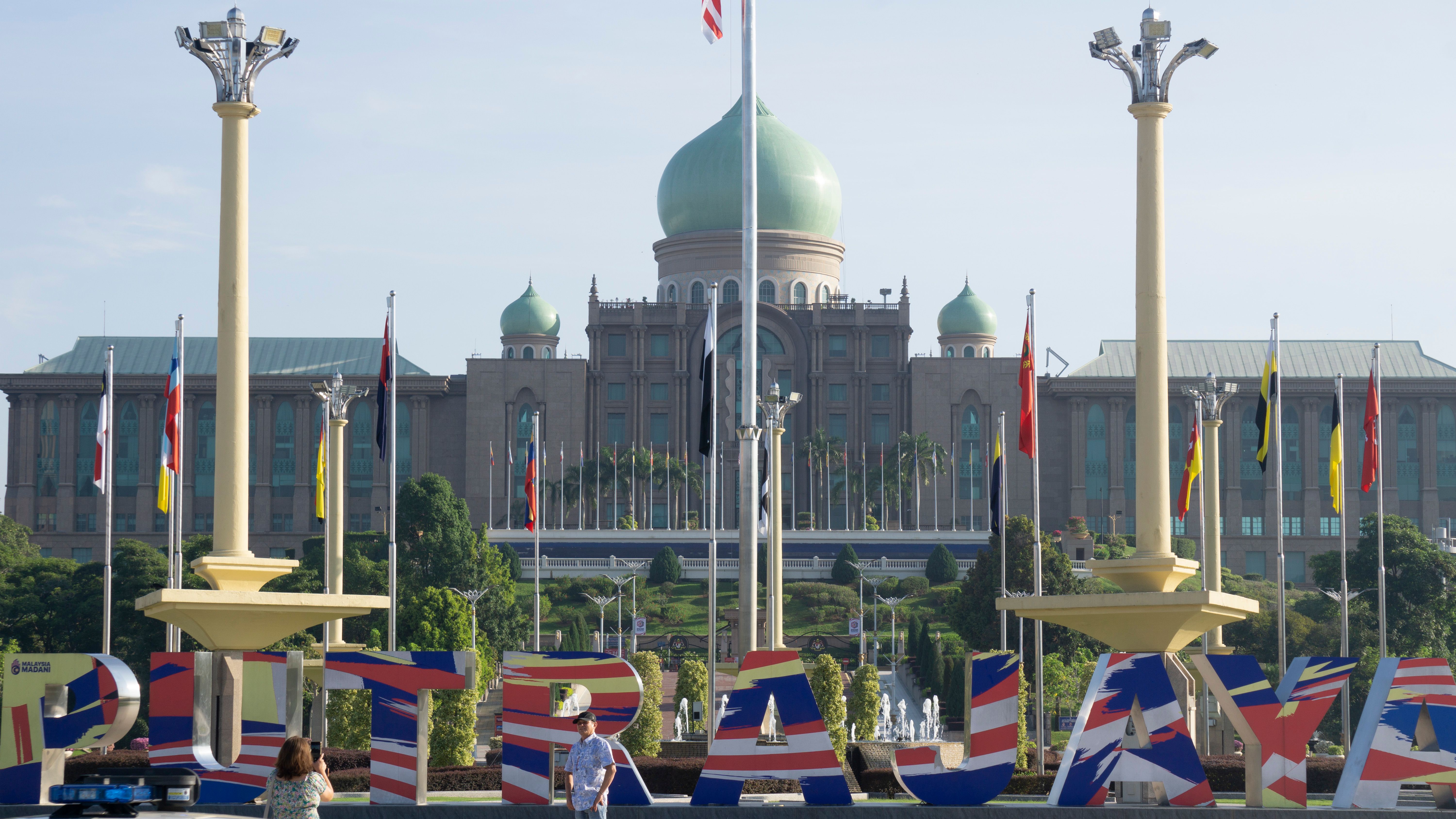 Putrajaya government building with national flags, symbolizing Malaysia's federal coalition politics