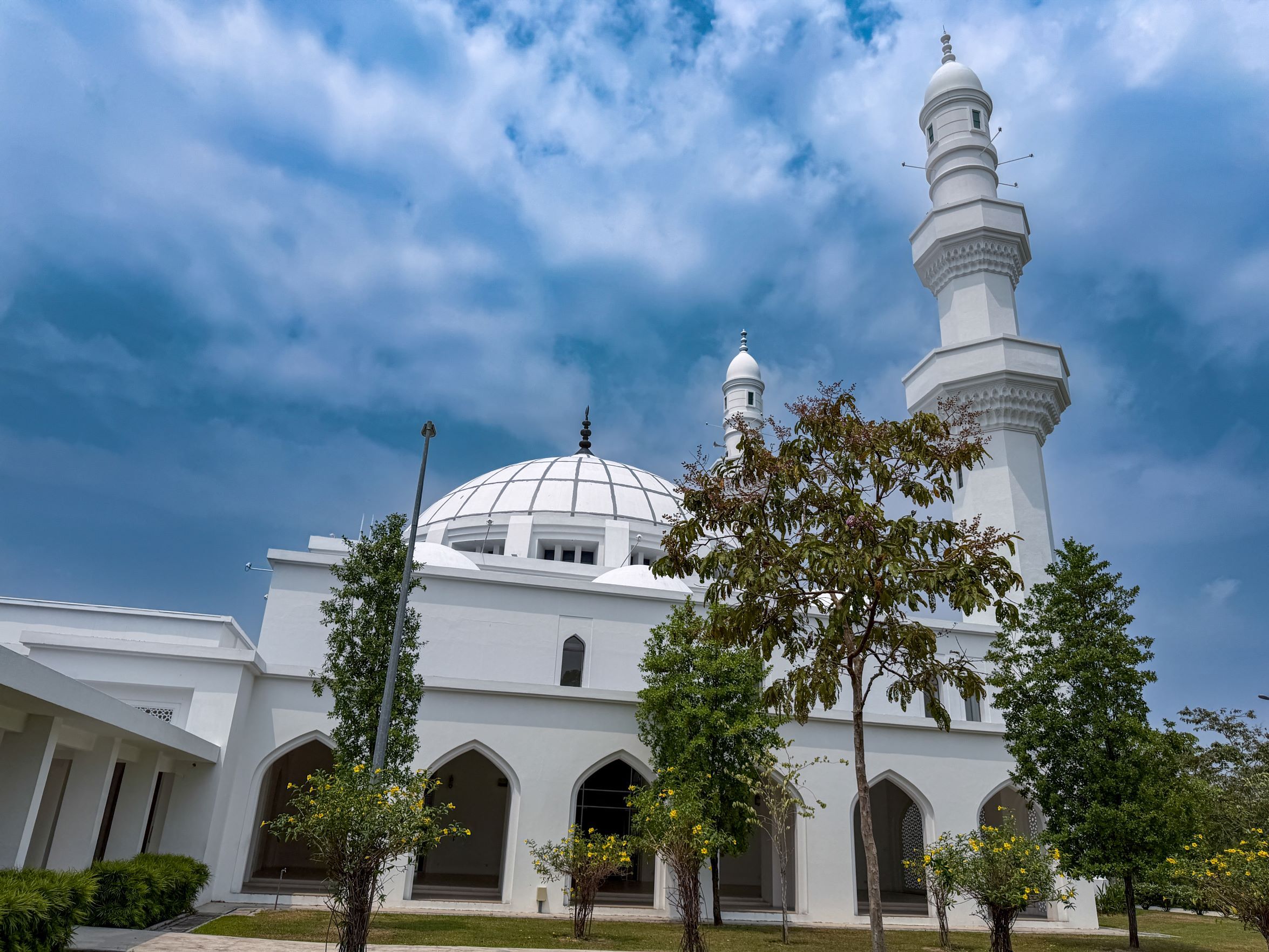 Modern white mosque with dome and minaret in Seremban, Negeri Sembilan under a blue sky