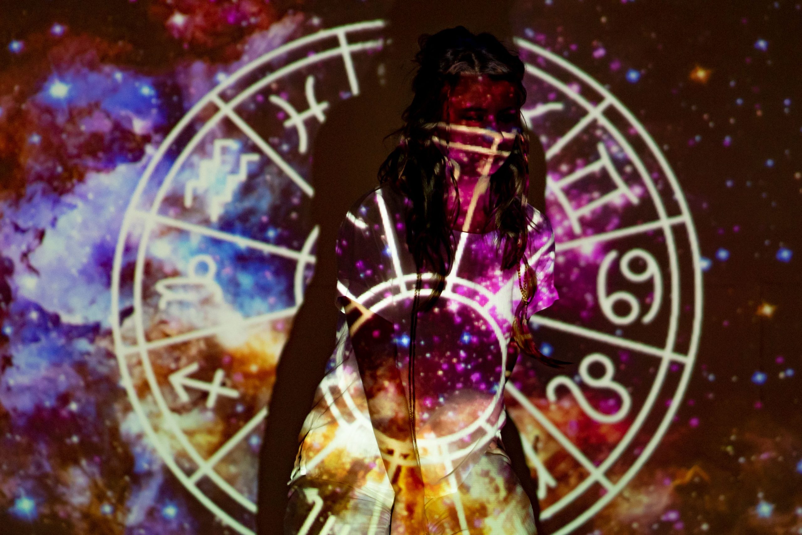 Woman surrounded by projected celestial and astrological symbols, evoking astrology and romantic destiny.