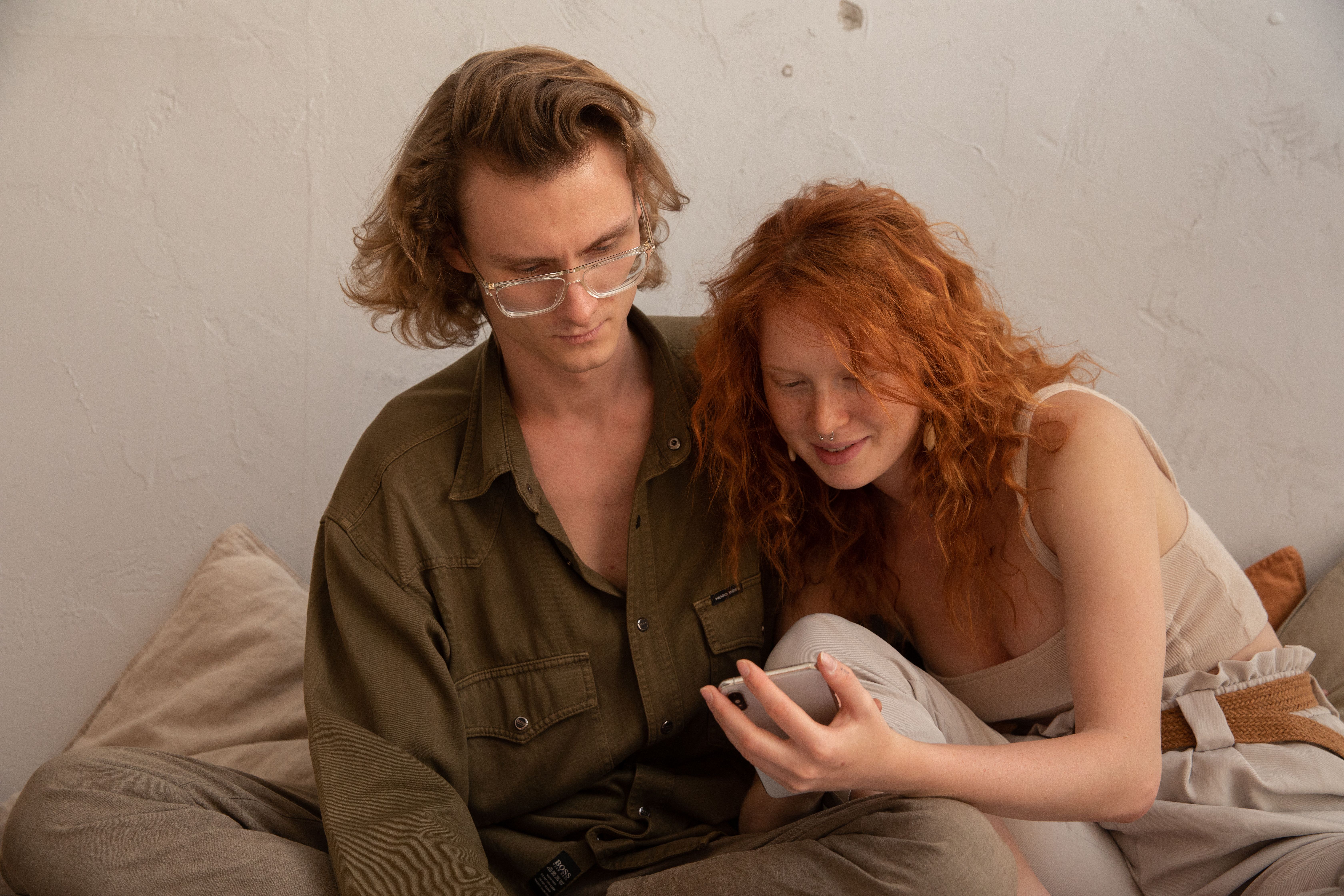 Couple relaxing together and looking at a smartphone, sharing a private online moment.