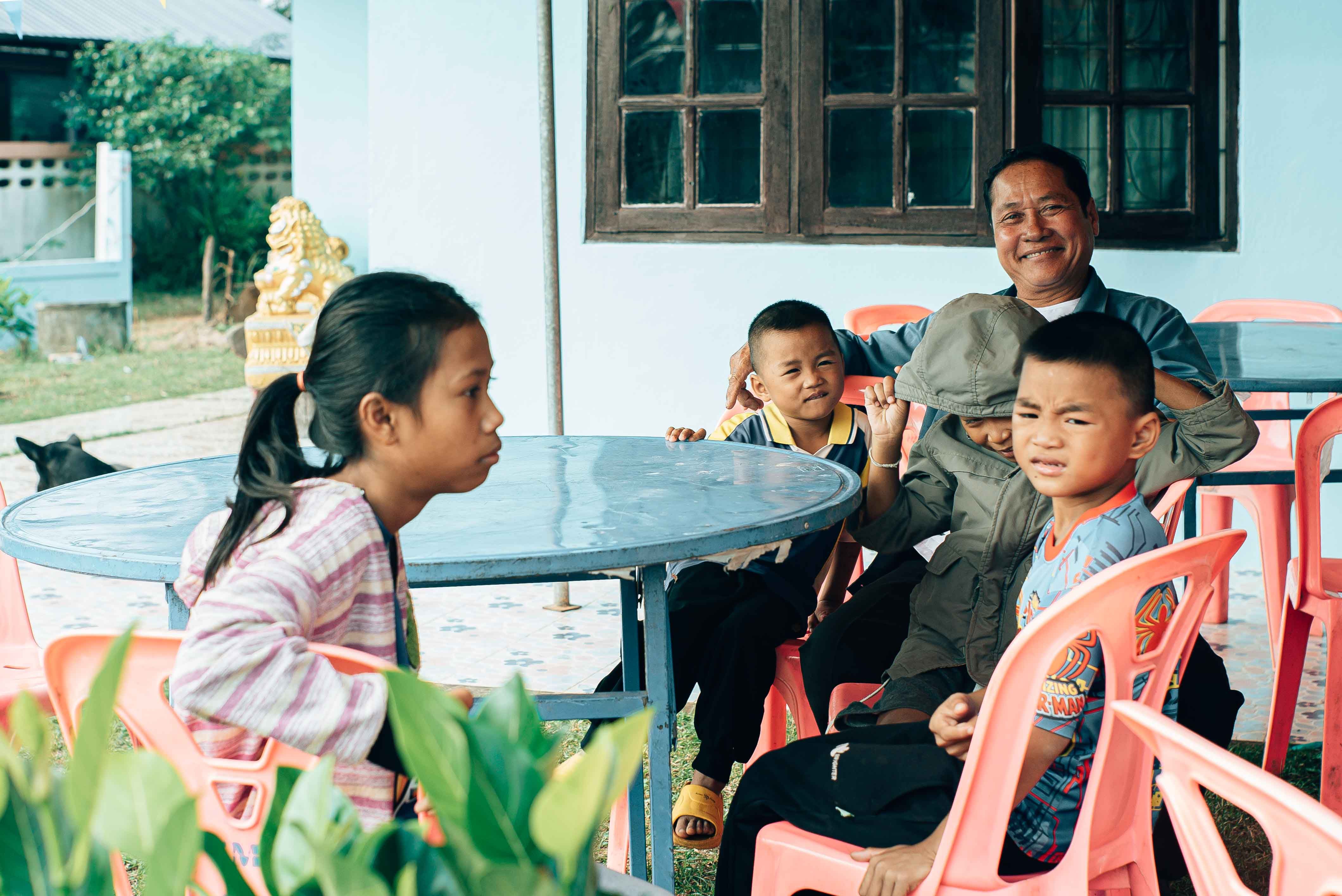 A family enjoying an outdoor gathering in Mukdahan, Thailand, around a shared table