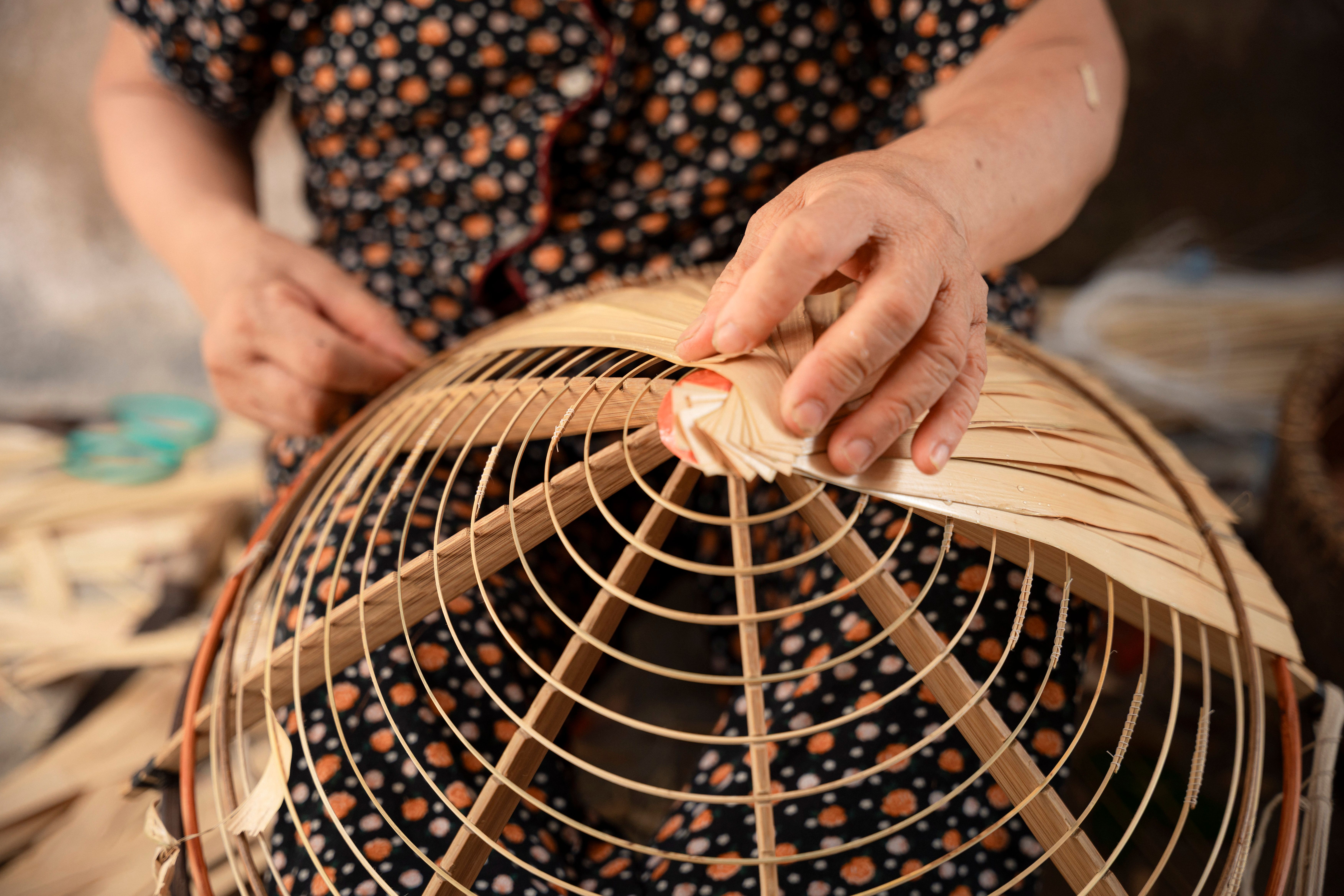 Close-up of a person weaving a traditional Vietnamese bamboo basket by hand